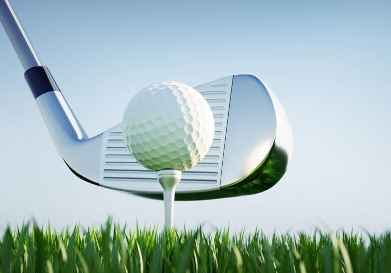 Golf club about to hit ball on tee.